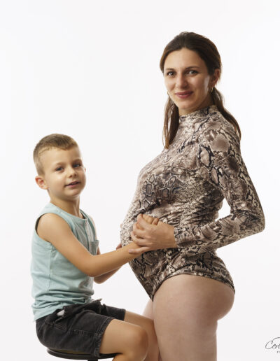 Moment complice entre une femme enceinte et son aîné lors d’une séance photo de grossesse en studio à Pontenx-les-Forges