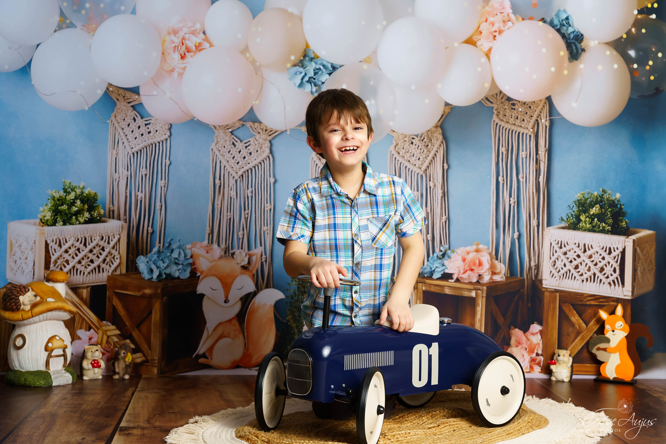 Enfant souriant avec porteur bleu dans décor Foxette boho renards macramé fleurs