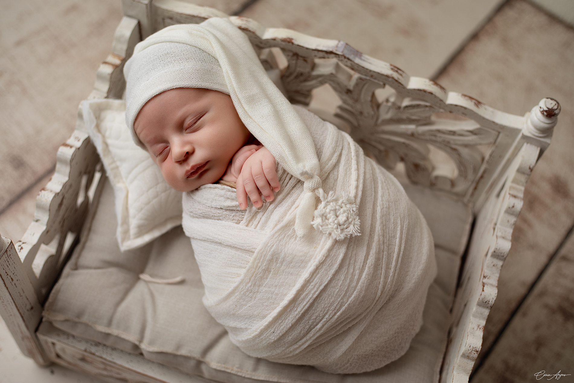 Bébé emmailloté dormant paisiblement sur un petit lit en studio photo près de Mimizan