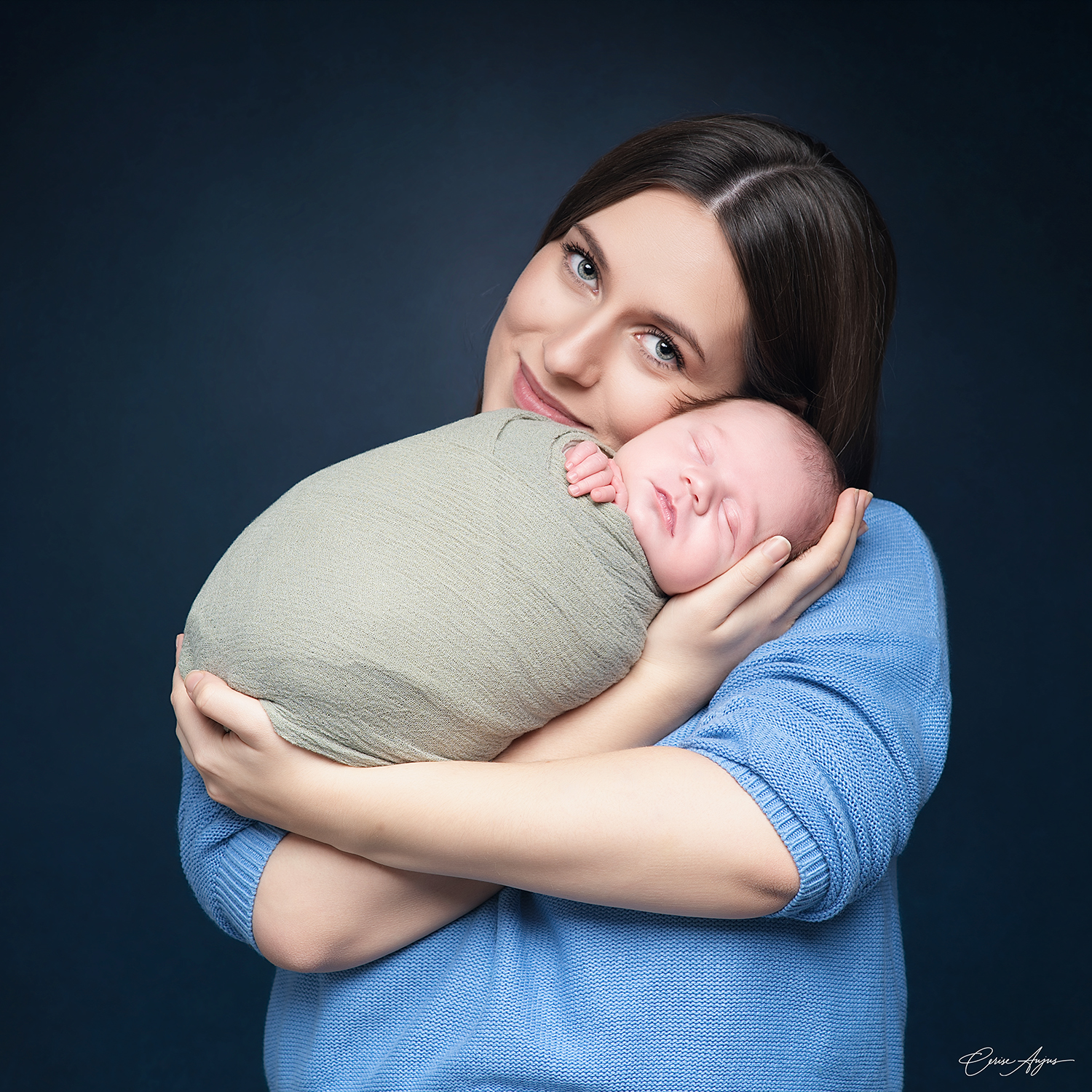 Mère tenant son bébé emmailloté dans les bras, tête contre tête, regard tendre vers l’objectif lors d’une séance photo naissance près de Mimizan