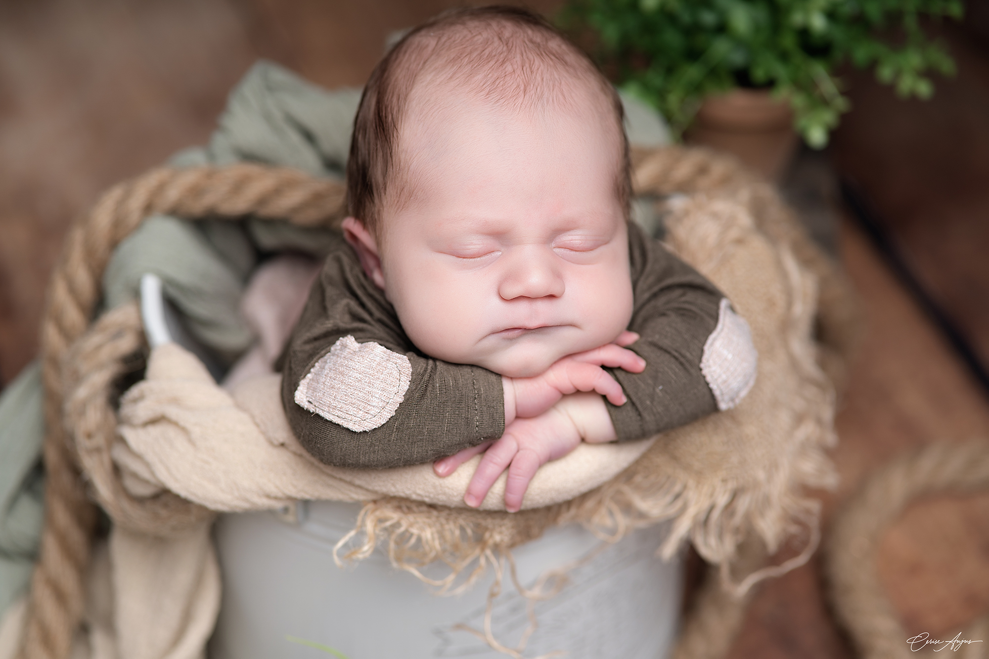 Bébé endormi en position chin on hands avec bonnet de meunier dans un contenant lors d’une séance photo naissance à Mimizan