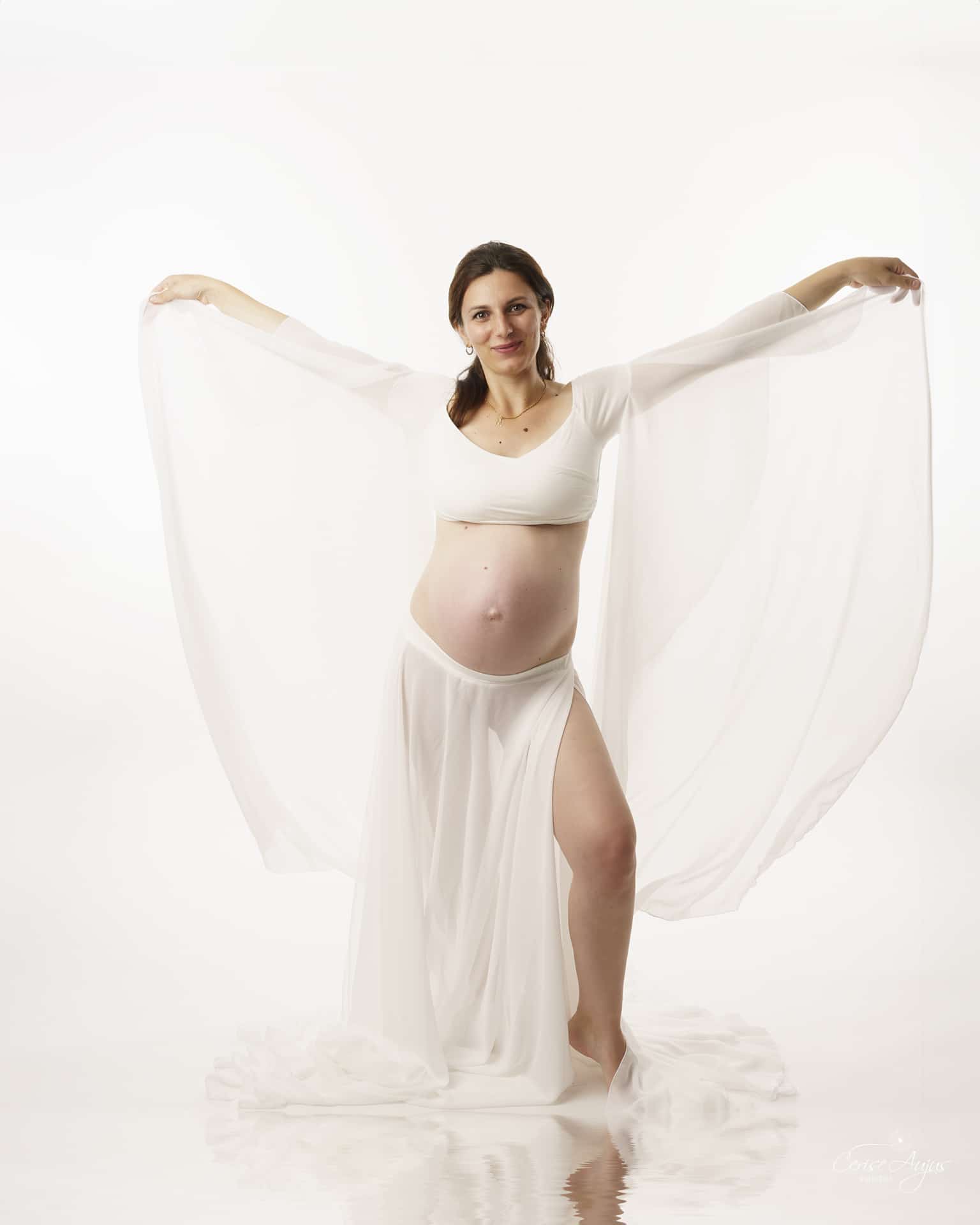 Femme enceinte en voile blanc volant, séance photo grossesse en studio près de Biscarrosse dans les Landes