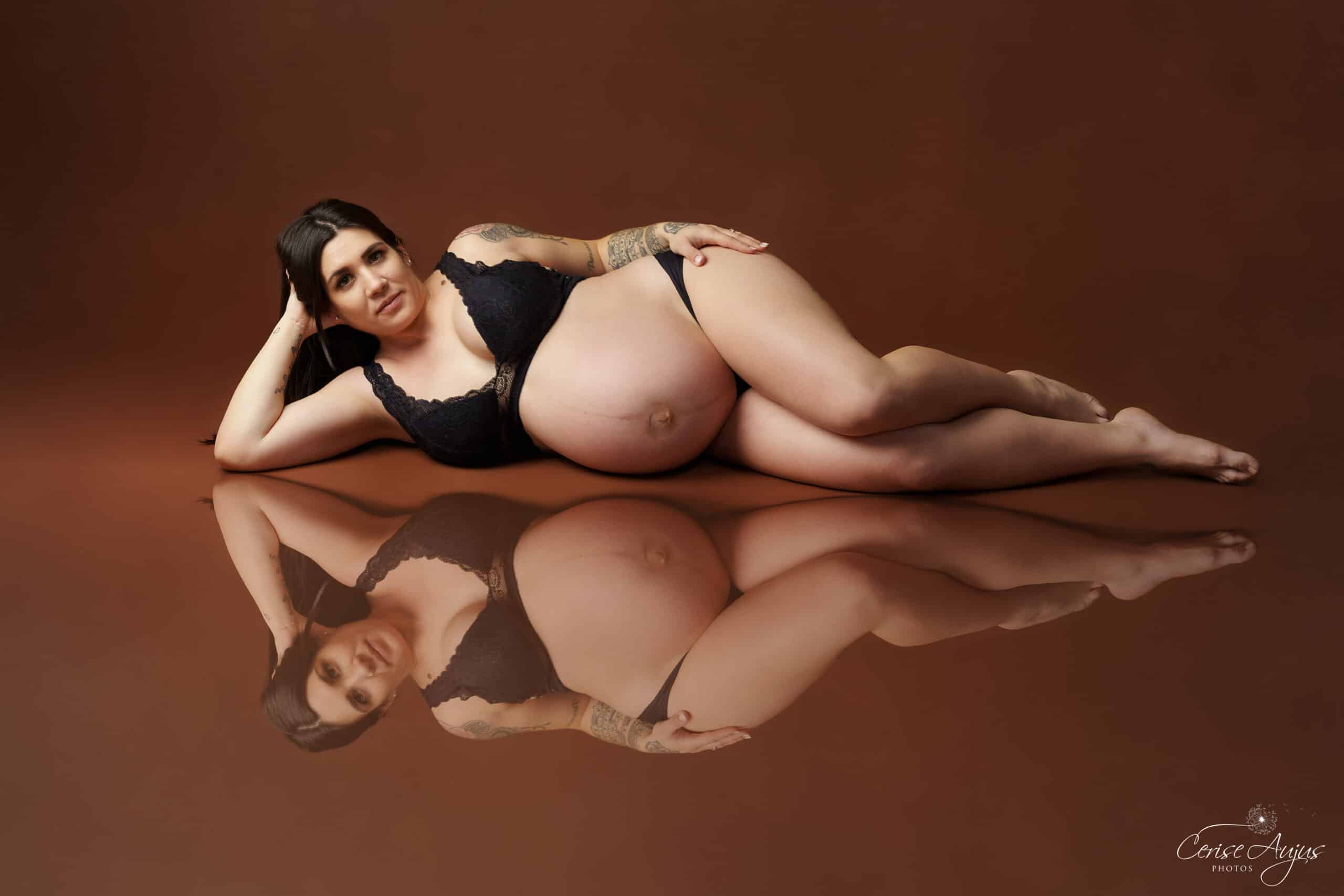 Femme enceinte au 9e mois allongée en lingerie noire, séance photo grossesse en studio dans les Landes