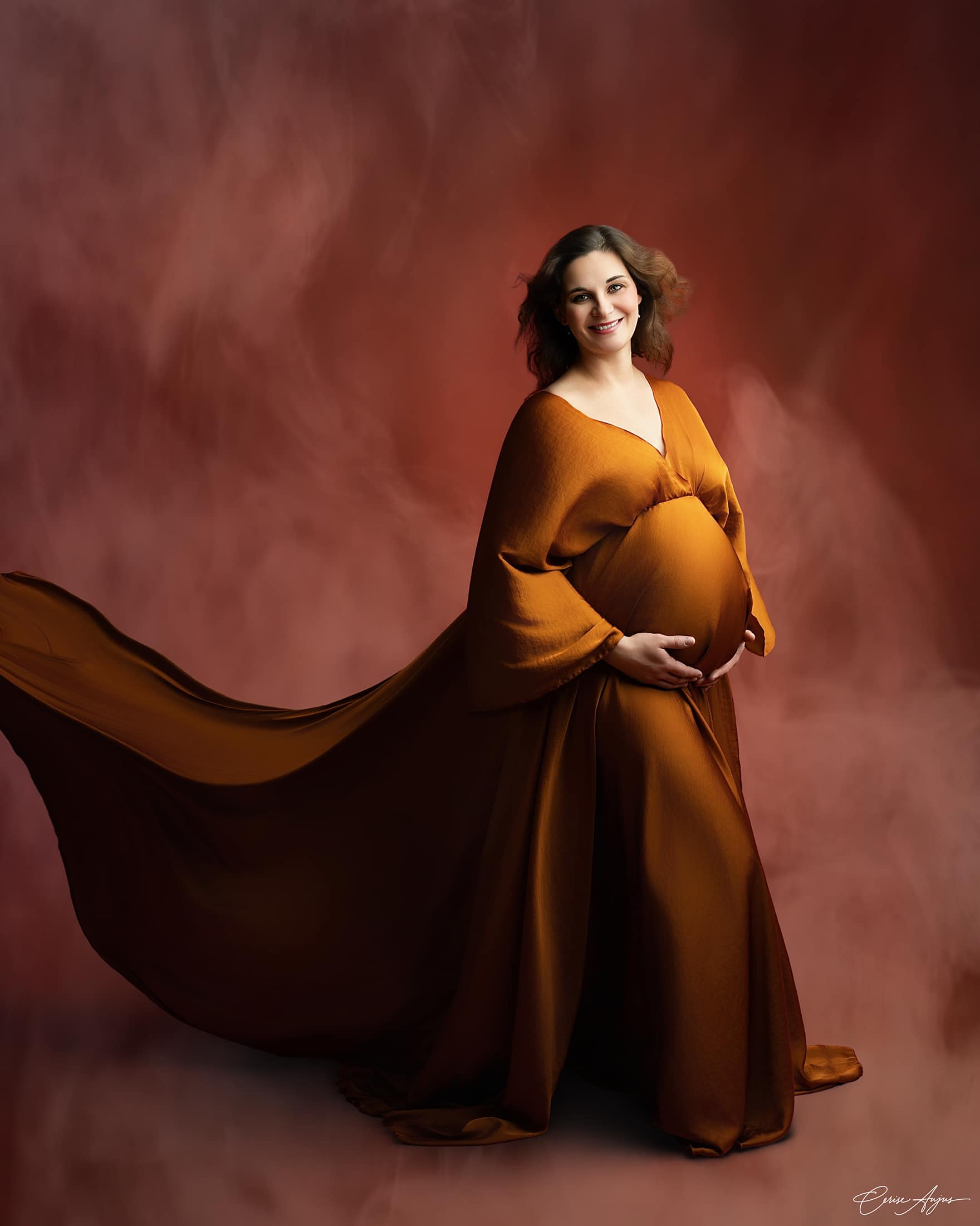 Femme enceinte souriante en robe cognac volante, séance photo grossesse en studio nord des Landes<br />