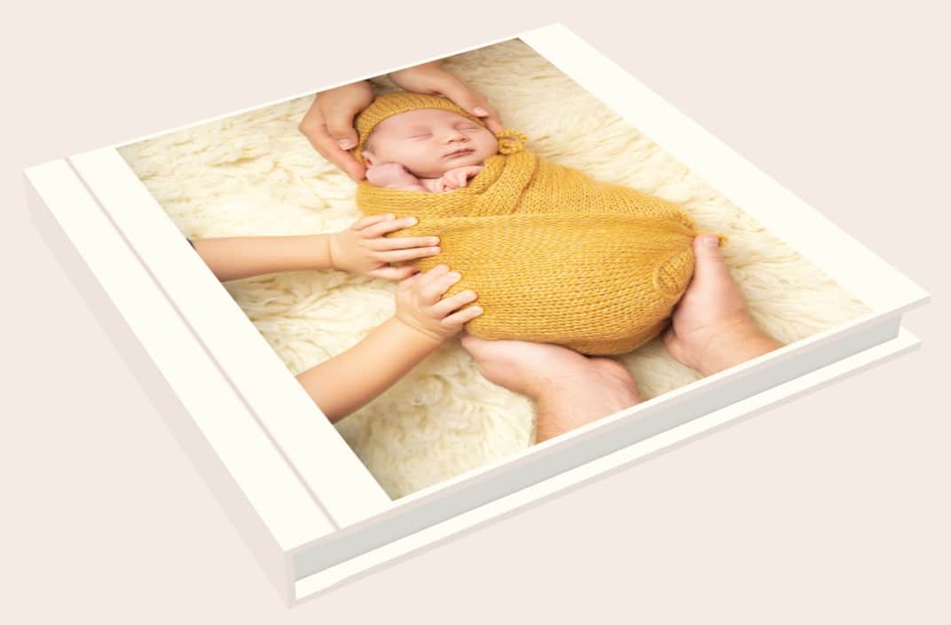 Album photo naissance ouvert avec portrait de nouveau-né emmailloté, photographe Landes